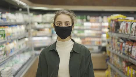 Mujer-Compradora-Hace-Compras-Durante-La-Epidemia-De-Coronavirus,-Camina-Por-La-Tienda-Con-Una-Máscara-Protectora