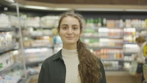 Portrait-of-the-young-beautiful-woman-smiling-happily-to-the-camera-at-the-grocery-supermarket
