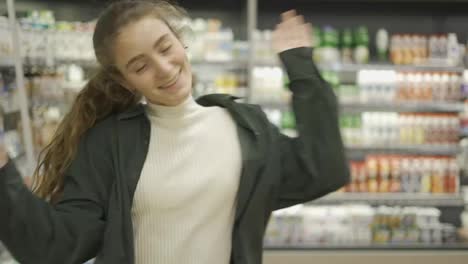 Fröhliches-Junges-Mädchen-Tanzt-Lustig-Zwischen-Den-Regalen-Im-Supermarkt