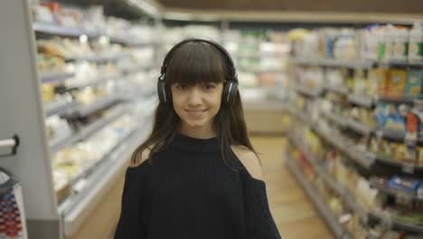 Adolescente-Sonriente-Caminando-En-El-Supermercado-Con-Auriculares