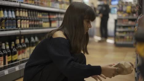 Close-up-footage-of-a-girl-in-the-store-taking-product-from-the-lower-shelf