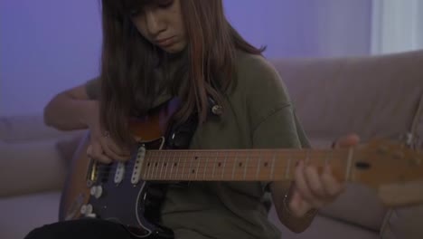 Teen-girl-learns-to-play-the-guitar,-closeup