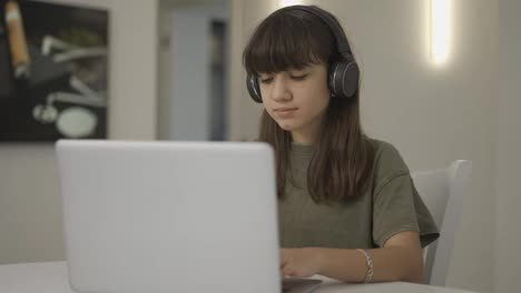 Portrait-of-the-cute-teen-girl-in-the-headphones-sitting-in-front-of-the-laptop