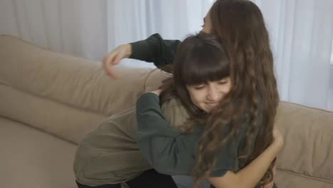 Close-relationship.-Affectionate-young-Mom-and-daughter-hug-on-couch-home