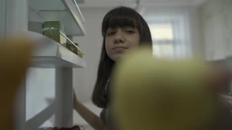 Young-pretty-girl-taking-yellow-apple-from-fridge