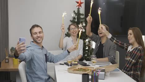 Cheerful-office-colleagues-celebrating-Christmas-corporate-party,-waving-with-golden-sparkles