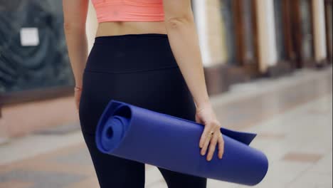 Closeup-woman-with-mat-came-to-a-beautiful-passage-place-for-her-training
