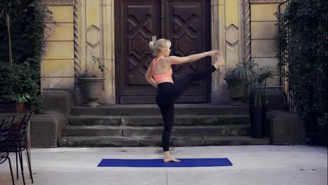 Frau-Macht-Yoga-über-Der-Veranda-Mit-Großer-Holztür