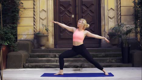 Mujer-En-La-Estera-Haciendo-Yoga-Sobre-El-Porche-Con-Una-Gran-Puerta-De-Madera