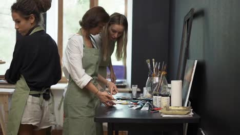 Women-pours-diverse-paint-into-a-palette-on-workshop