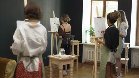 Group-of-students-painting-at-art-lesson-in-studio-in-slowmo