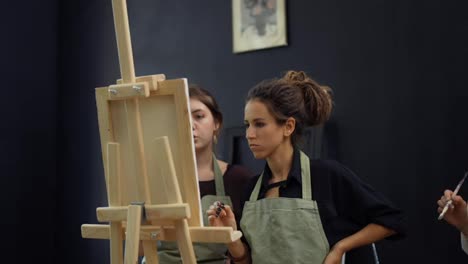 Student-and-art-teacher-during-painting-lesson-standing-in-front-the-easel