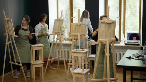 Four-female-students-painting-at-art-lesson-in-art-studio