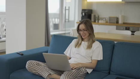 Blonde-woman-make-video-call-online-chat-look-at-laptop-screen-sit-on-sofa