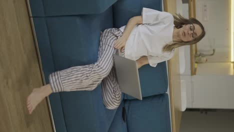 Blonde-woman-in-pajama-sit-on-the-couch-and-opens-the-silver-laptop