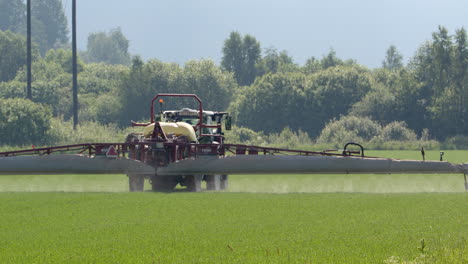 Crops-on-farm-land-sprayed-with-crop-sprayer-behind-tractor
