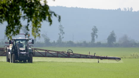 Farmer-with-sprayer-tractor-spraying-crops-with-wide-boom-arm,-Hedemora,-Sweden