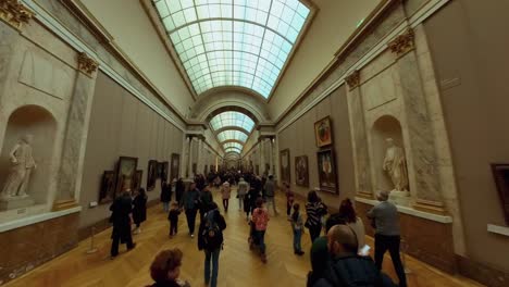 Dolly-above-tourists-admiring-artwork-inside-of-Louvre-Paris