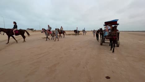 Reverse-tracking-shot-of-tourists-enjoying-horse-caravan-in-Djerba-dry-salt-lake-desert-in-Tunisia