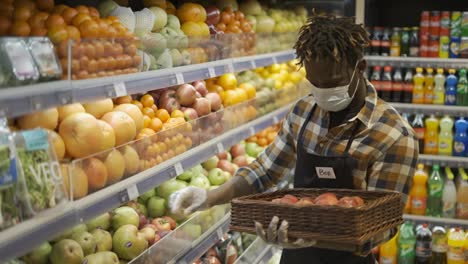 African-american-worker-arranging-storage-racks-in-fruit-department