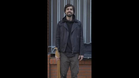 Man-smiling-on-the-street-and-carrying-a-guitar