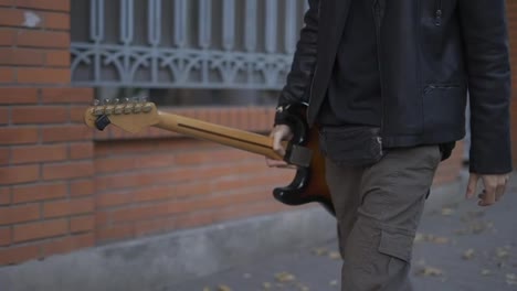 Man-walking-down-the-street-with-a-guitar