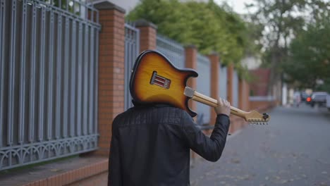 Man-walking-down-the-street-with-a-guitar-on-his-shoulder