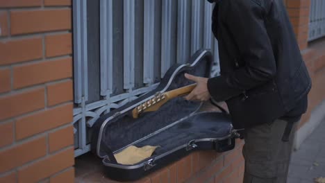Mann-Legt-Die-Gitarre-In-Den-Koffer