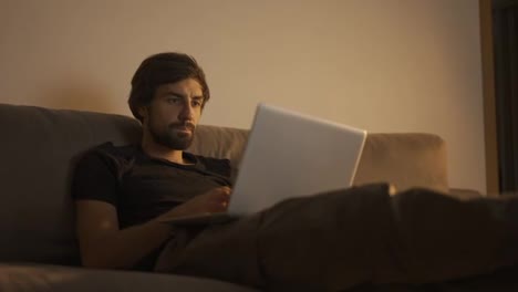 Hombre-Concentrado-Trabajando-En-Una-Laptop-En-Casa-Mientras-Se-Sienta-En-El-Sofá