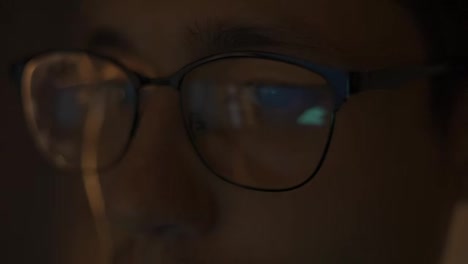 Man-Traiding-at-night-looking-at-monitor,-reflections-in-eyeglasses