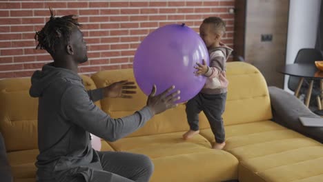 Afroamerikanischer-Vater-Spielt-Mit-Süßem-Kleinen-Jungen-Auf-Dem-Sofa-Im-Gemütlichen-Wohnambiente