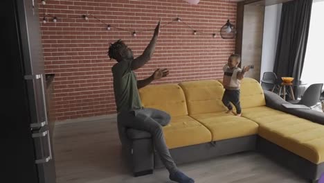 Afroamerikanischer-Vater-Spielt-Mit-Kleinem-Jungen-Und-Wirft-Sich-Gegenseitig-Luftballons-Zu