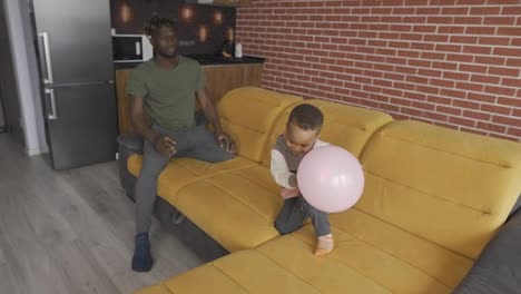 Afroamerikanischer-Vater-Spielt-Mit-Kleinem-Jungen,-Wirft-Ballon,-Zeitlupe
