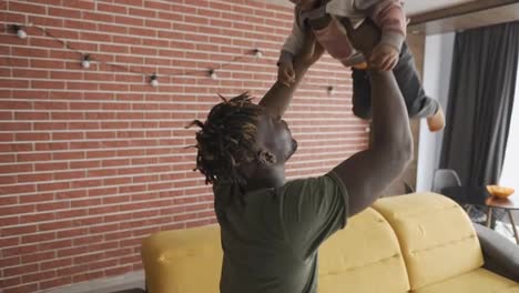 Playful-father-raising-his-toddler-son-up-in-air