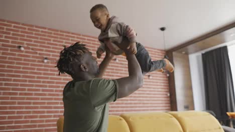 Playful-father-raising-his-toddler-son-up-in-air,-slow-motion