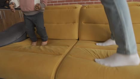Cropped-body-multiethnic-father-and-toddler-son-jumping-on-couch