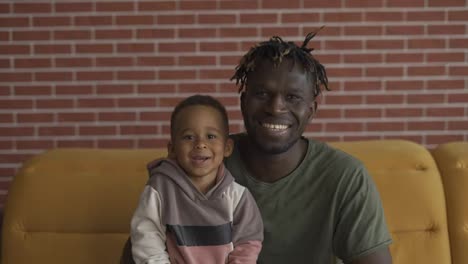 Mixed-race-family-dad-child-boy-happy-faces-sit-on-sofa-bonding,-closeup-portrait