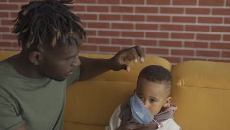 Black-dad-putting-on-protective-mask-on-son's-face-before-walk,-slow-motion