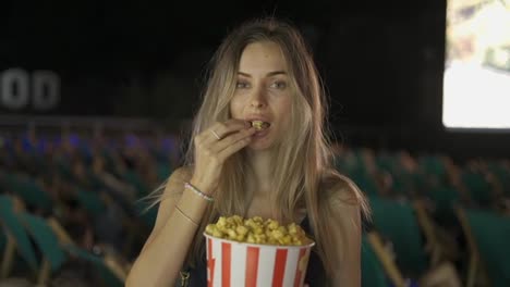 Portrait-of-charming-lovely-blonde-taking-popcorn-inside-cinema-hall