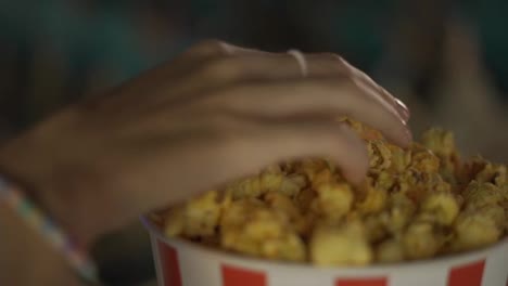 Cinema,-movies-and-entertainment-concept---female-hands-take-a-popcorn