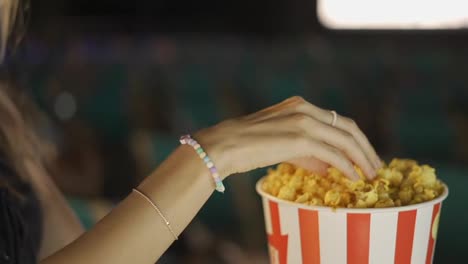 Smiling-lovely-blonde-taking-popcorn-at-the-cinema