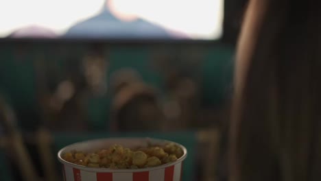 Footage-over-shoulder---woman-eats-popcorn-at-the-cinema