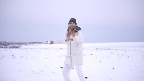 Girl-throwing-snowball-at-camera-smiling-happy-having-fun-outdoors