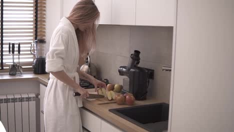 Woman-at-kitchen-cutting-apple-with-a-knife-on-a-wooden-cutting-board