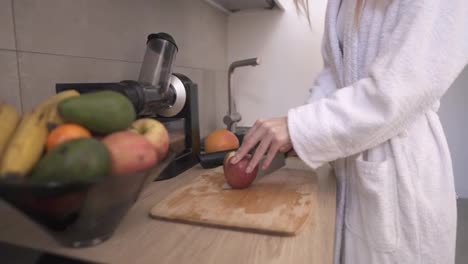 Woman-cutting-apple-with-a-knife-on-a-wooden-cutting-board-to-make-juice