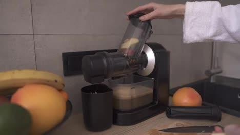 Woman-prepare-apple-or-pear-juice-in-the-morning-using-juicer-at-kitchen