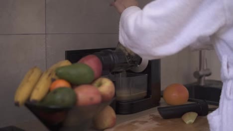 Frau-Presst-Morgens-Apfel--Oder-Birnensaft-Mit-Einem-Entsafter-In-Der-Küche