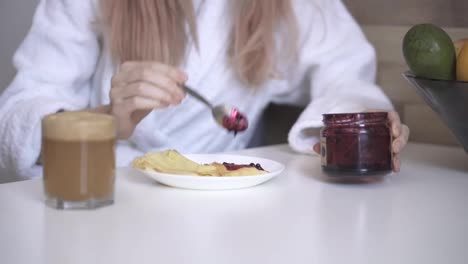 Woman-has-breakfast-pancakes-with-berry-jam-and-fresh-apple-juice-at-home