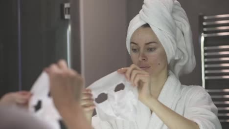 Portrait-of-a-woman-in-bathrobe-putting-white-mask-for-moisturizing
