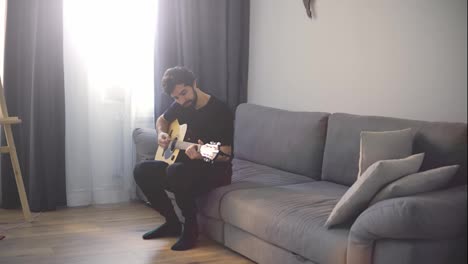 Portrait-of-a-man-with-a-guitar-in-his-hands-on-sofa
